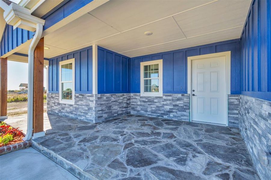 Doorway to property featuring board and batten siding, covered porch, and stone siding Doorway to property featuring board and batten siding, covered porch, and stone siding