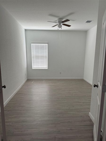 Well-lit room featuring durable laminate flooring and a ceiling fan for comfort.