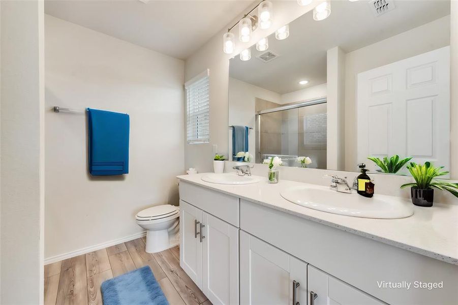 Bathroom with LVP flooring, double sink, toilet, and large vanity