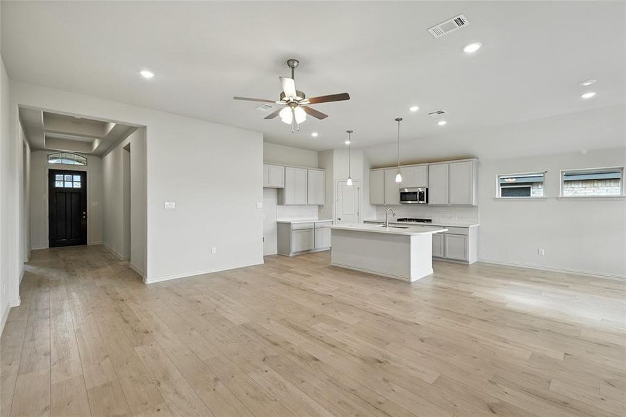 Kitchen featuring light wood-style flooring, recessed lighting, ceiling fan, stainless steel microwave, and decorative light fixtures Kitchen featuring light wood-style flooring, recessed lighting, ceiling fan, stainless steel microwave, and decorative light fixtures