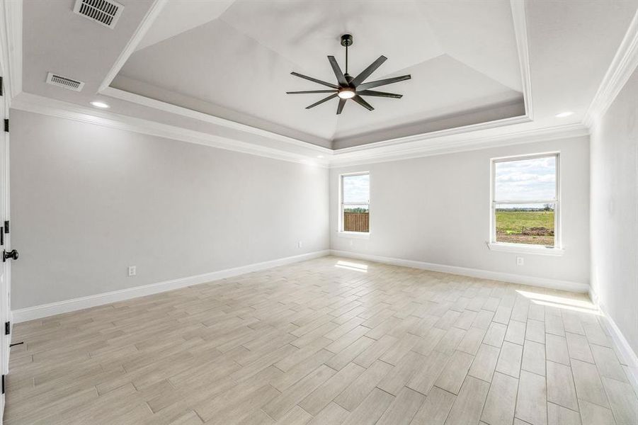 Empty room with ornamental molding, a tray ceiling, light wood-type flooring, a ceiling fan, and recessed lighting