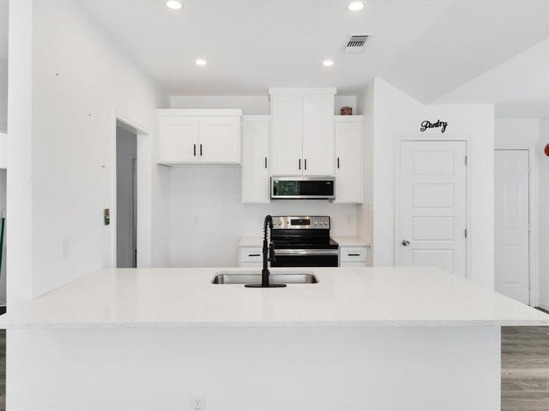 Modern kitchen featuring a spacious island with an undermount sink and black faucet