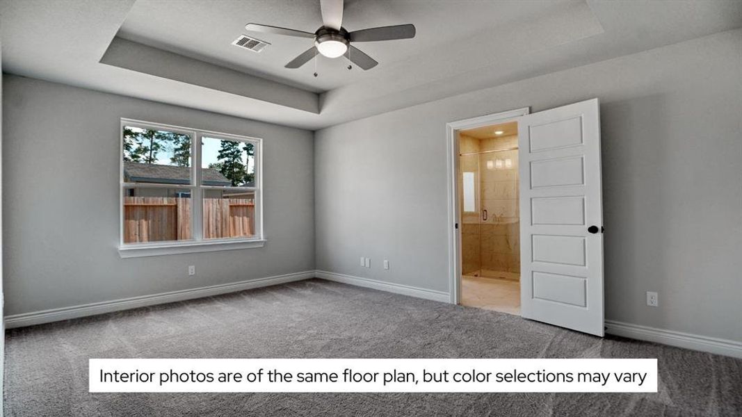 The spacious primary bedroom has a tray ceiling and ceiling fan.