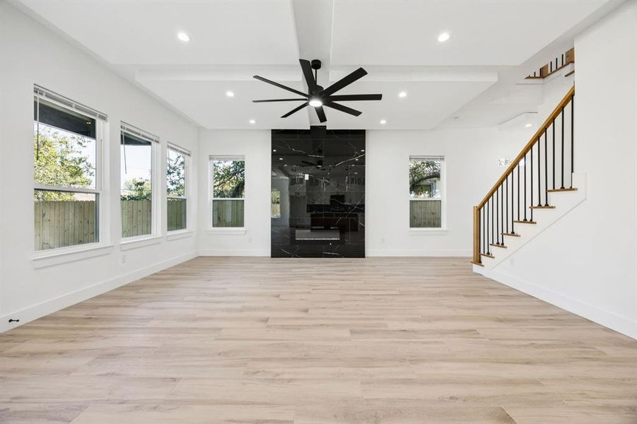 Unfurnished living room featuring light wood finished floors, beam ceiling, stairs, recessed lighting, and ceiling fan