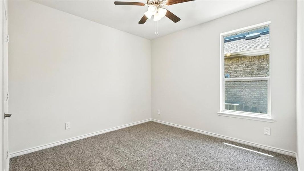 Carpeted empty room featuring a ceiling fan and baseboards