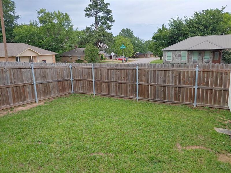 Fenced backyard featuring a wood privacy fence with metal posts, green lawn, and a corner configuration