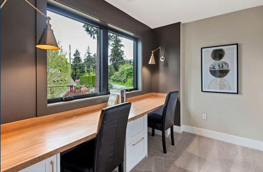 Office space featuring light colored carpet and built in study area