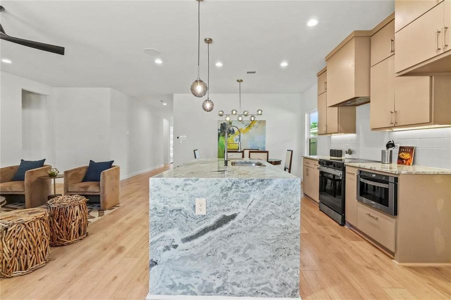 Kitchen featuring light stone countertops, tasteful backsplash, recessed lighting, hanging light fixtures, and electric range Kitchen featuring light stone countertops, tasteful backsplash, recessed lighting, hanging light fixtures, and electric range