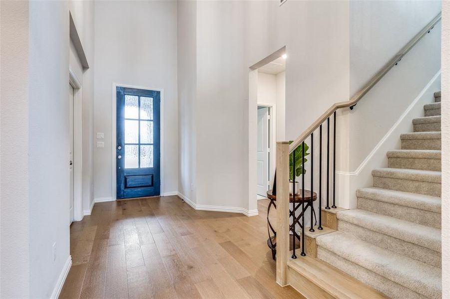 Foyer entrance with light wood-type flooring and a towering ceiling