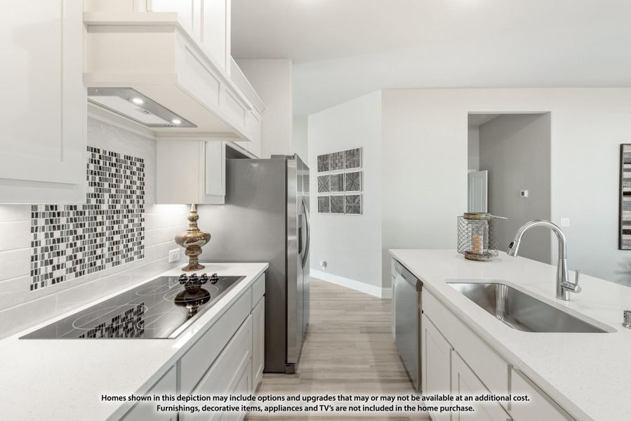 Kitchen with white cabinets, mosaic tile backsplash, stainless appliances, and undermount sink with light wood floors