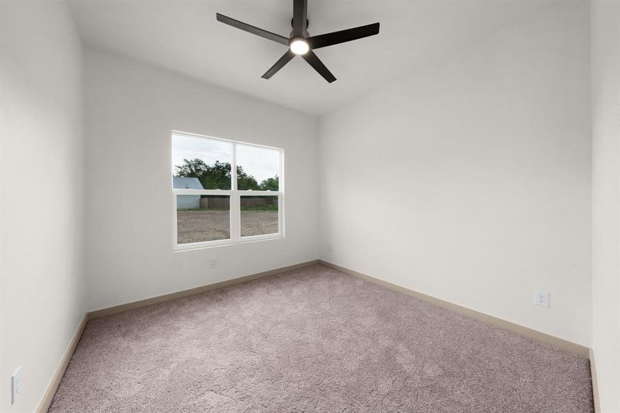 Empty room featuring baseboards, carpet, and a ceiling fan
