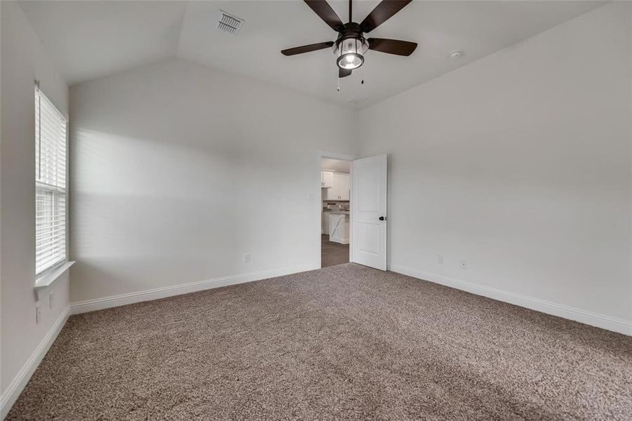 Unfurnished bedroom featuring vaulted ceiling, carpet flooring, and ceiling fan