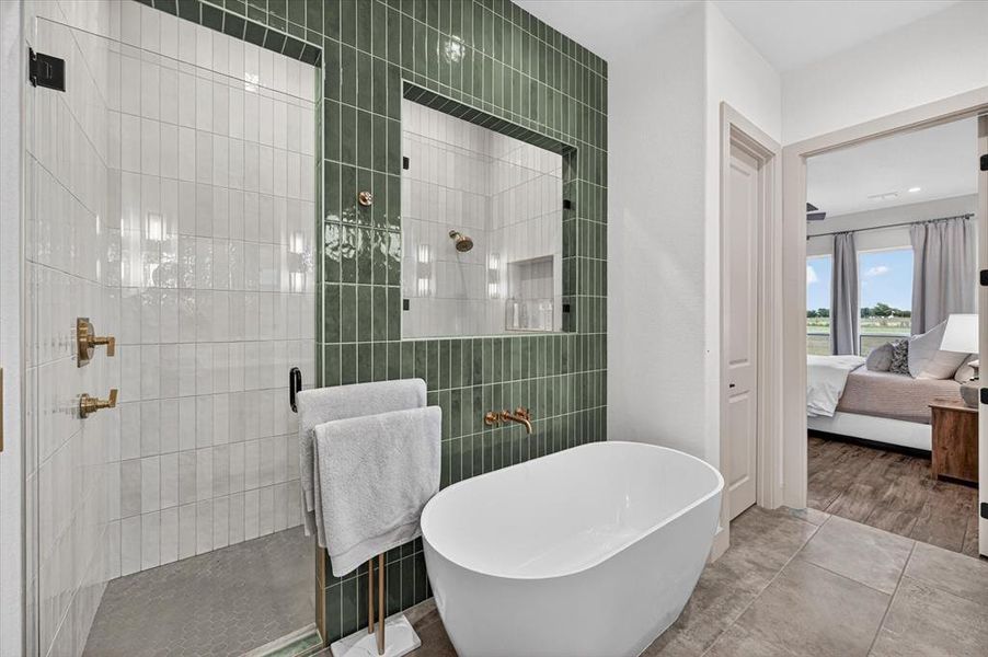 Freestanding soaking tub with a wall-mounted brass faucet, complemented by a walk-in shower featuring a glass enclosure and a textured green tile accent wall