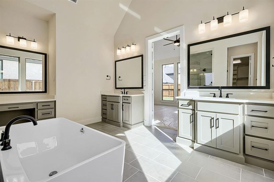Bathroom featuring two vanities, a soaking tub, light tile patterned floors, a ceiling fan, and vaulted ceiling Bathroom featuring two vanities, a soaking tub, light tile patterned floors, a ceiling fan, and vaulted ceiling