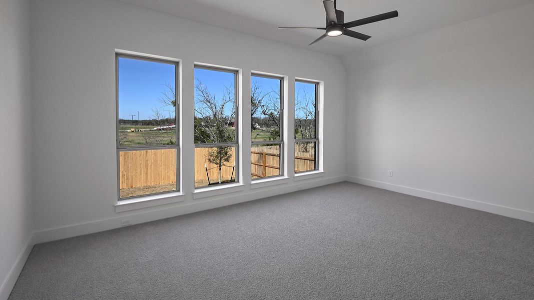 Carpeted spare room with a ceiling fan and baseboards