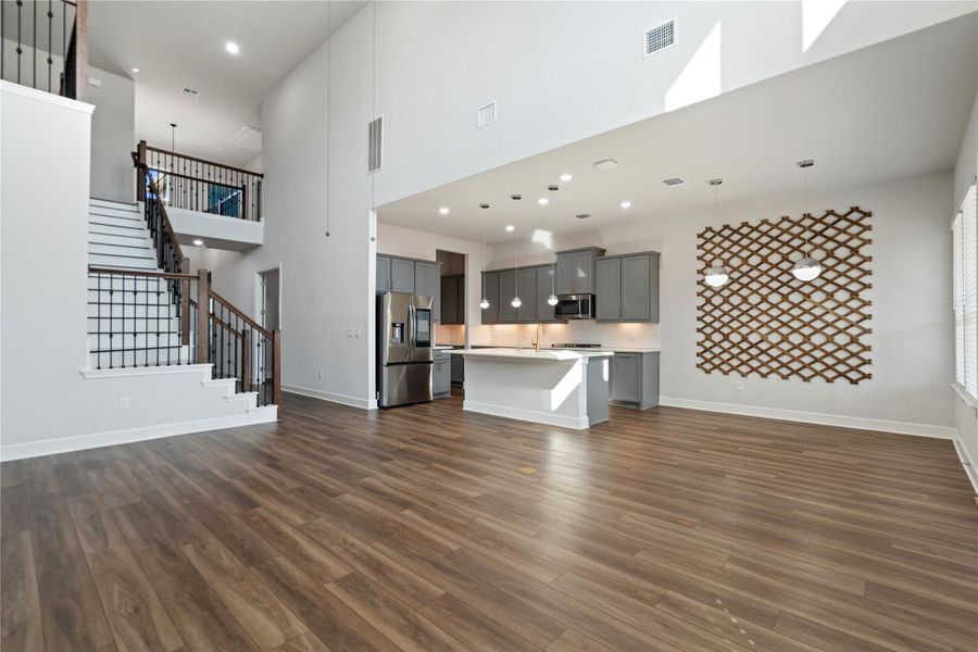 Warm wood flooring flows throughout a soaring living space connected directly to the kitchen.