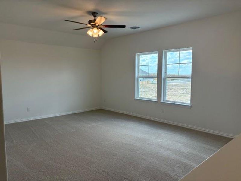 Empty room featuring light carpet, vaulted ceiling, and a ceiling fan Empty room featuring light carpet, vaulted ceiling, and a ceiling fan