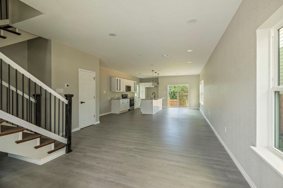 Unfurnished living room featuring stairs, light wood finished floors, and recessed lighting