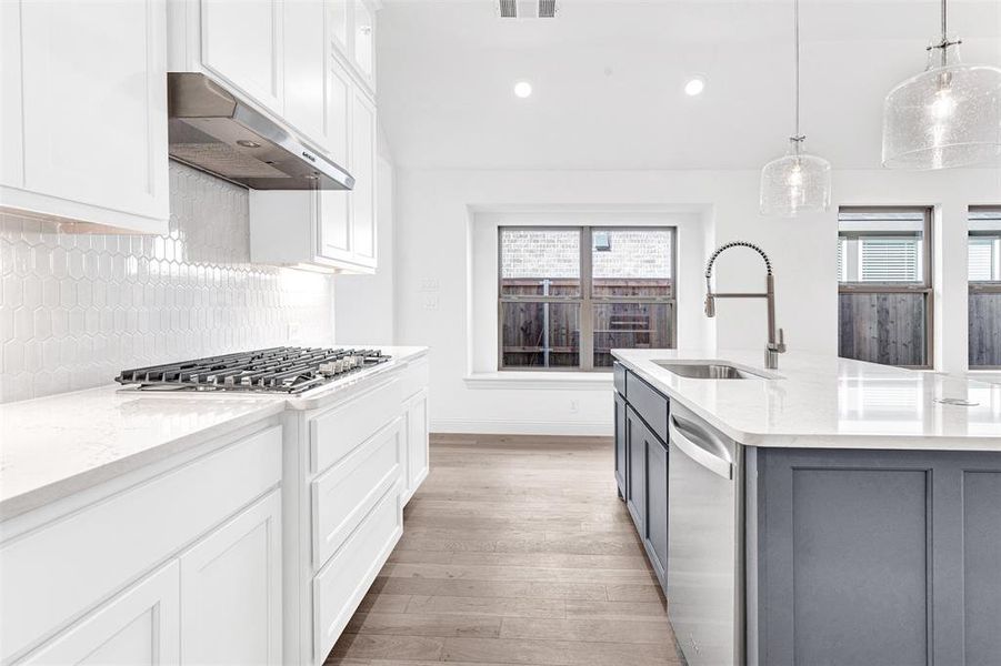 Kitchen with sink, stainless steel appliances, an island with sink, white cabinets, and exhaust hood