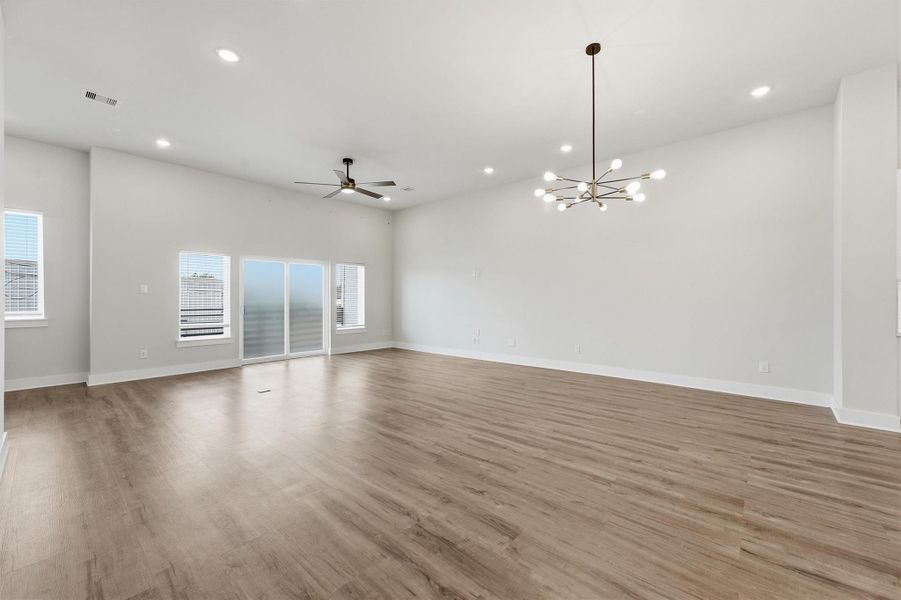 Spacious open-concept living and dining area featuring wide-plank flooring, modern lighting fixtures, recessed lights, and abundant natural light with access to a private balcony.