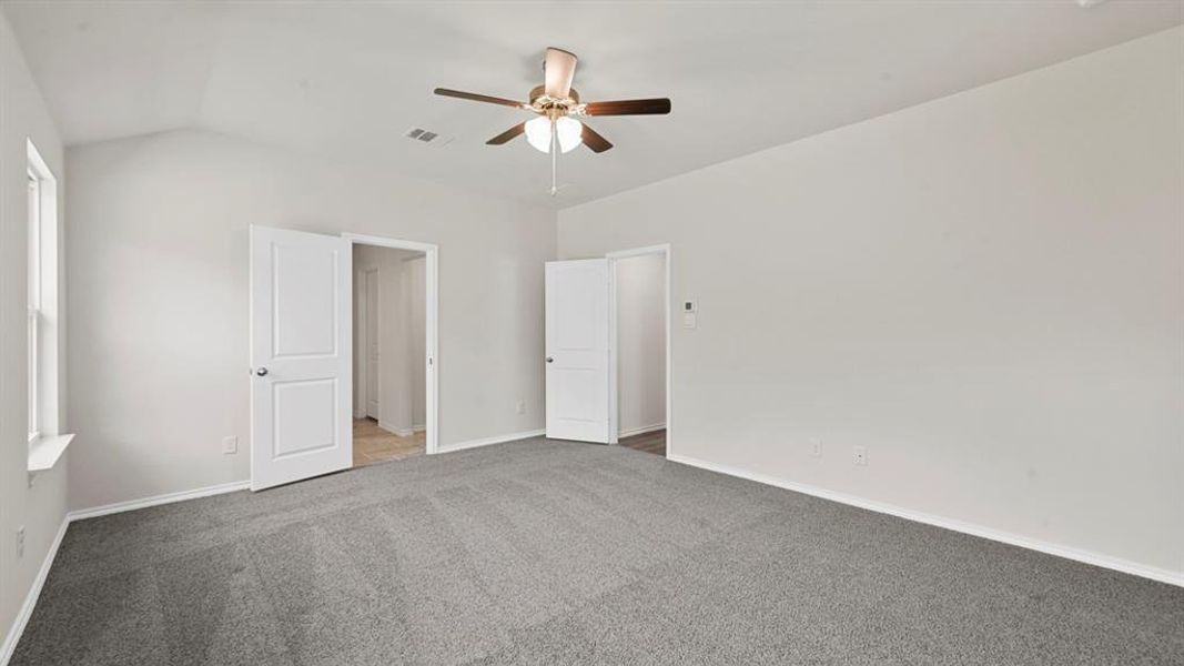 Carpeted room featuring a vaulted ceiling and a ceiling fan with integrated lighting Carpeted room featuring a vaulted ceiling and a ceiling fan with integrated lighting