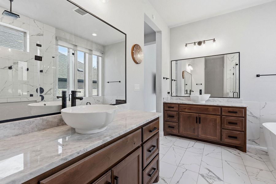 Marble-clad floors and vanity tops grace this bathroom, featuring vessel sinks and a spacious shower. Marble-clad floors and vanity tops grace this bathroom, featuring vessel sinks and a spacious shower.
