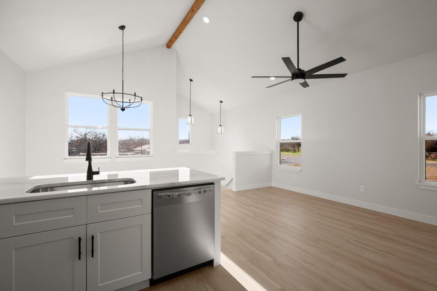 Kitchen with dishwasher, light wood-type flooring, open floor plan, hanging light fixtures, and light stone countertops