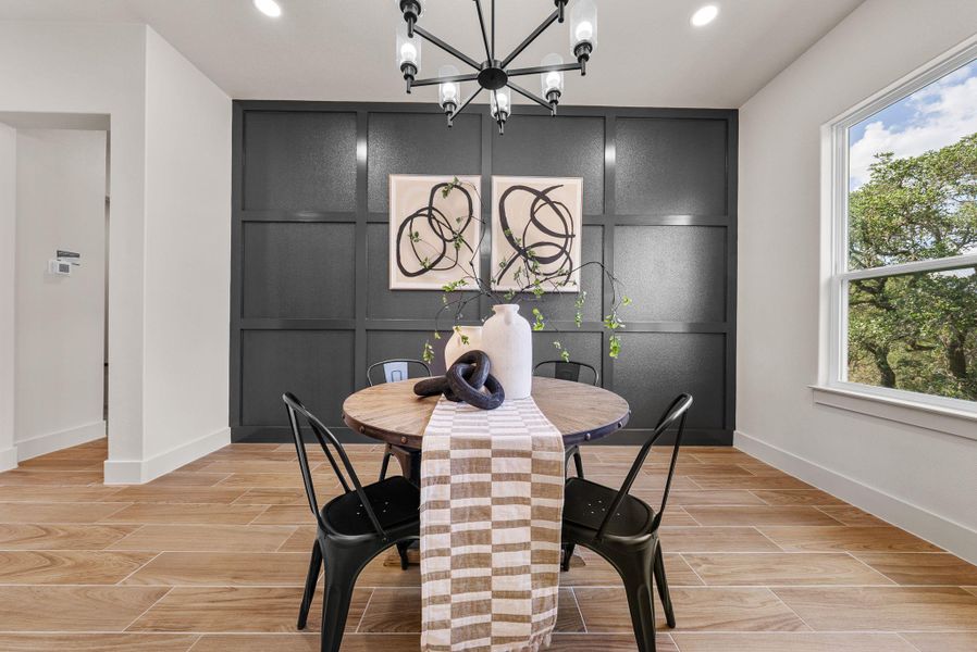 A striking accent wall elevates this well-lit dining space, complemented by wide plank tile flooring and ample natural light.