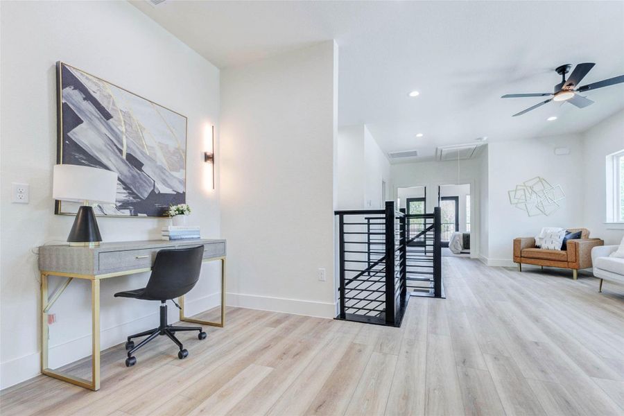 Versatile wide-plank flooring extends throughout the upstairs landing, which includes dedicated wall space for a workstation or console.