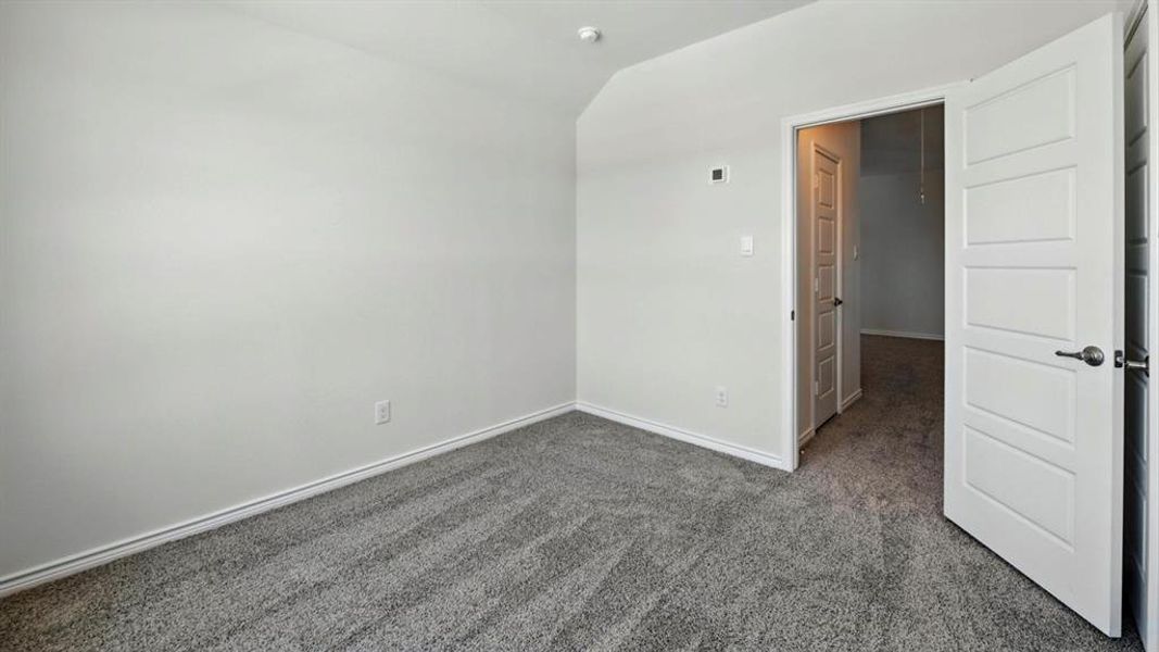 Unfurnished room featuring dark carpet and vaulted ceiling