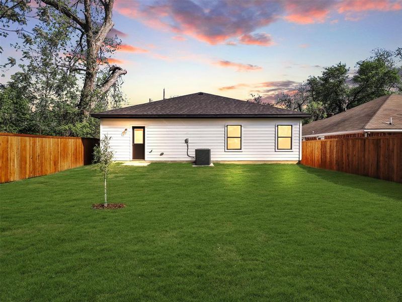 Back of house featuring a fenced backyard, a yard, and cooling unit Back of house featuring a fenced backyard, a yard, and cooling unit