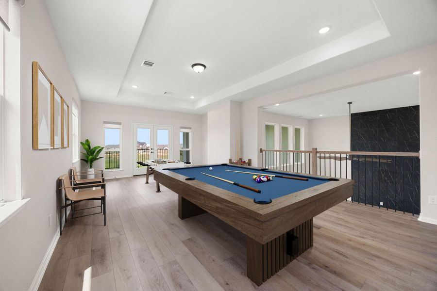 Massive upstairs game room loft offering the ultimate second-level entertainment hub. This expansive recreation space features a deep tray ceiling with recessed lighting, premium wide-plank flooring. Wrought-iron railing borders the open catwalk overlooking the family room below, while double glass doors lead out to a private second-story balcony framing scenic lakefront views. *Virtually Staged Massive upstairs game room loft offering the ultimate second-level entertainment hub. This expansive recreation space features a deep tray ceiling with recessed lighting, premium wide-plank flooring. Wrought-iron railing borders the open catwalk overlooking the family room below, while double glass doors lead out to a private second-story balcony framing scenic lakefront views. *Virtually Staged