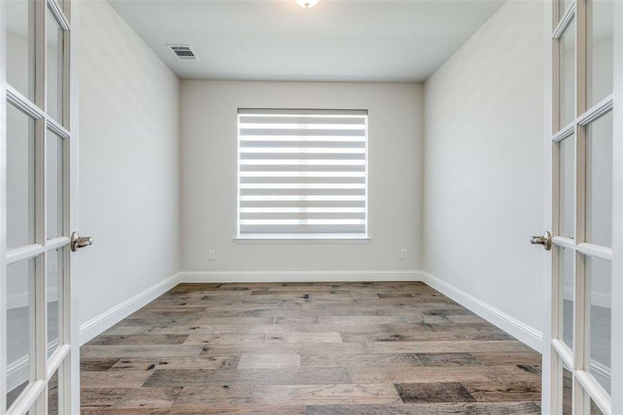 Empty room with french doors, wood finished floors, and baseboards