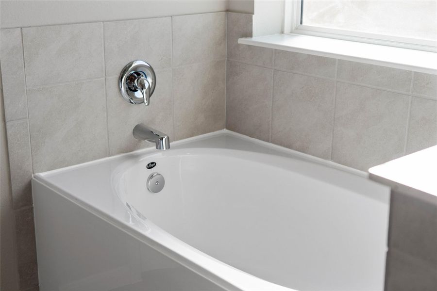 Indulge in the primary bath's deep, built-in soaking tub with elegant chrome fixtures and a sleek tile surround for a true spa-like retreat. Indulge in the primary bath's deep, built-in soaking tub with elegant chrome fixtures and a sleek tile surround for a true spa-like retreat.