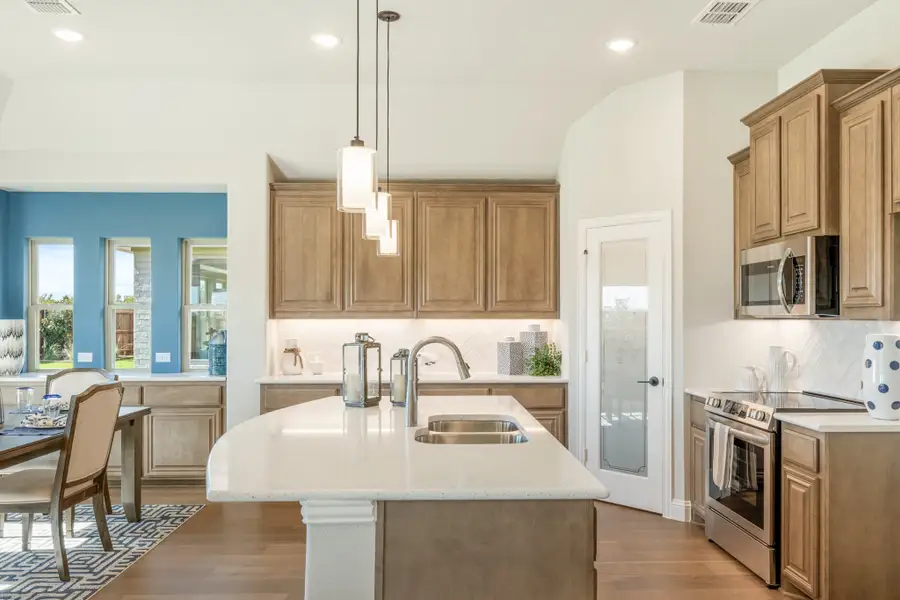 Kitchen with center island, quartz countertops, wood cabinets, stainless appliances, and pendant lights open to dining area