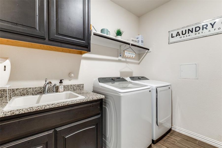 Laundry area featuring cabinets, dark wood-type flooring, sink, and washer and dryer