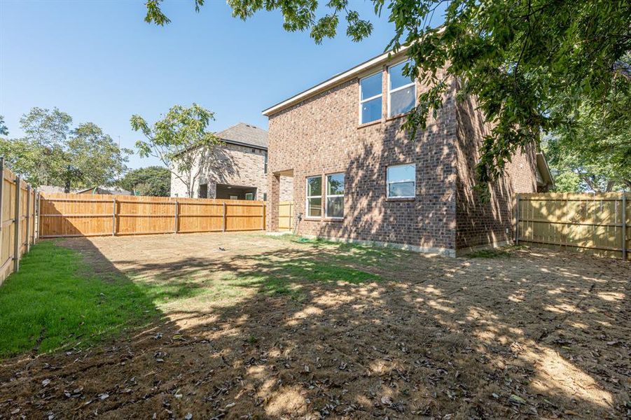 Rear view of house with a fenced backyard and brick siding