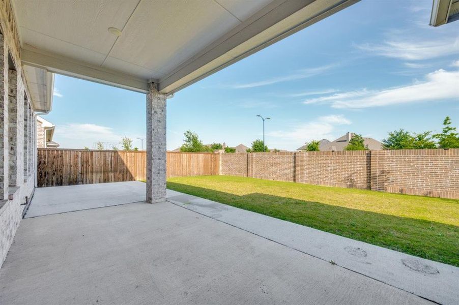 Expansive covered patio featuring a concrete surface, white brick columns, and a beadboard ceiling