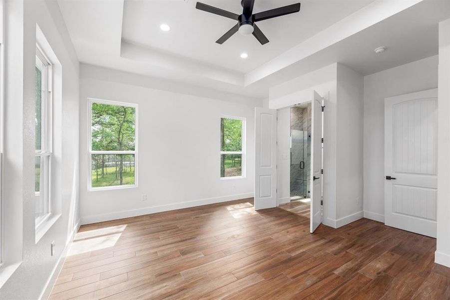 Primary bedroom with large windows, high ceilings, and a serene nature view!