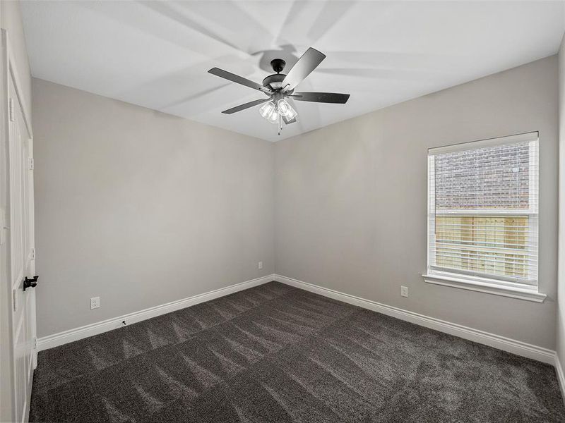 Spare room featuring dark carpet and ceiling fan Spare room featuring dark carpet and ceiling fan