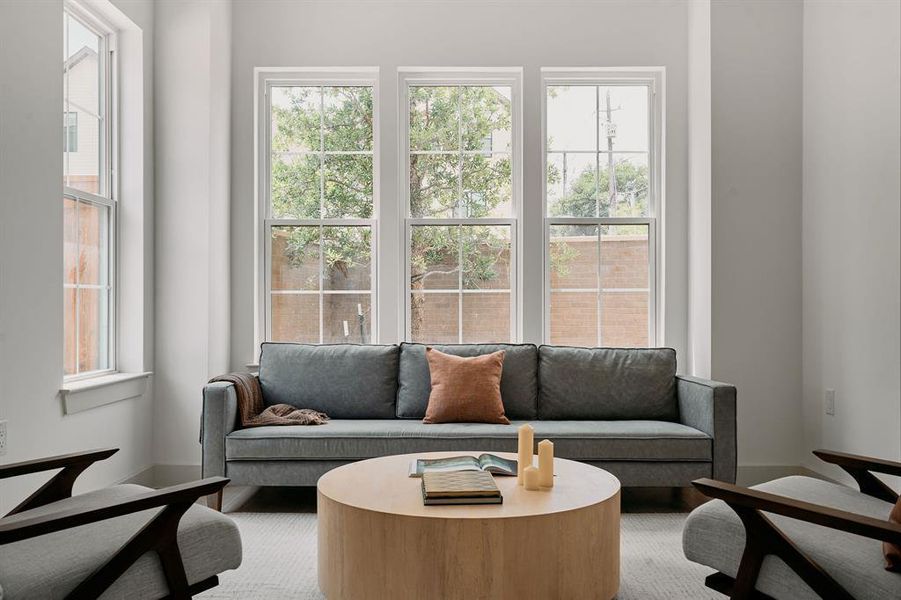 Bright living space featuring a trio of tall windows, white trim throughout, and light-toned walls