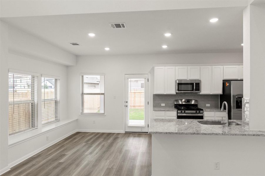 Kitchen featuring recessed lighting, white cabinets, appliances with stainless steel finishes, light wood-type flooring, and tasteful backsplash Kitchen featuring recessed lighting, white cabinets, appliances with stainless steel finishes, light wood-type flooring, and tasteful backsplash