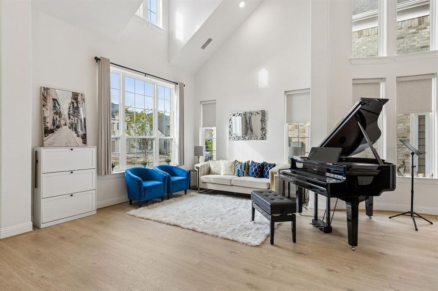 Spacious room featuring vaulted ceilings, light wood-finish flooring, and expansive windows