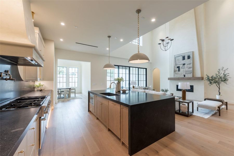 This perspective highlights the intentional flow of the main living space—where the curved plaster vent hood mirrors the fireplace’s sculptural form, and the European white oak floors unify the kitchen, dining, and living area. Oversized dark grid windows flood the space with natural light, accentuating the contrast between soft cream cabinetry, matte black stone, and brass details. This perspective highlights the intentional flow of the main living space—where the curved plaster vent hood mirrors the fireplace’s sculptural form, and the European white oak floors unify the kitchen, dining, and living area. Oversized dark grid windows flood the space with natural light, accentuating the contrast between soft cream cabinetry, matte black stone, and brass details.
