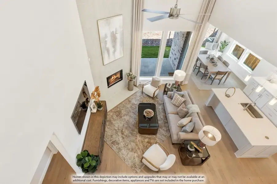 Open-concept living room with two-story ceiling, fireplace, and view into kitchen and dining area, shot from above.