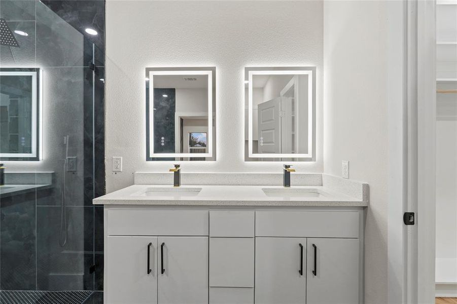 Bathroom with double vanity, a stall shower, and a textured wall