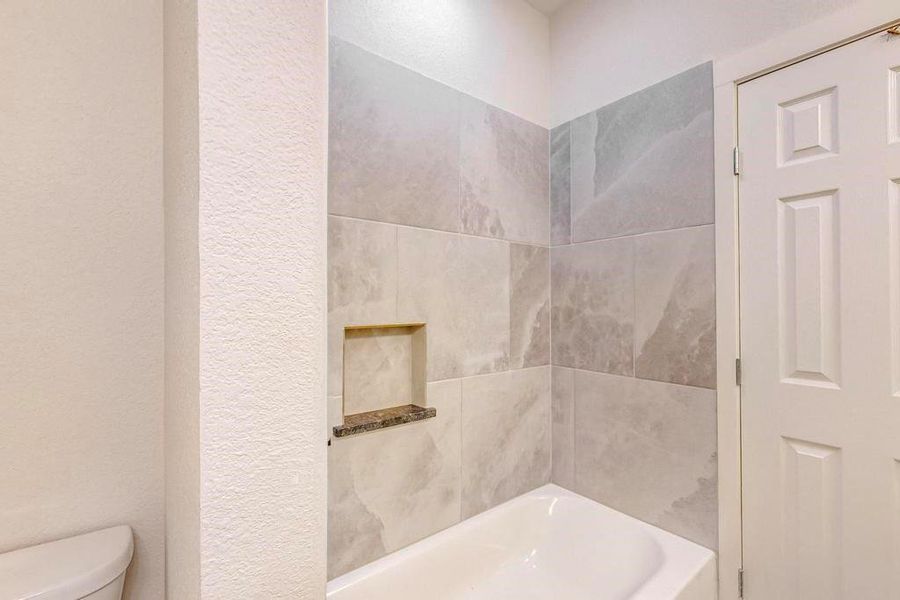 Bathroom featuring tiled shower / bath combo and toilet