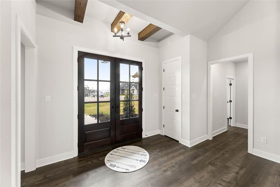 Foyer entrance with a chandelier, french doors, and dark wood-style flooring Foyer entrance with a chandelier, french doors, and dark wood-style flooring