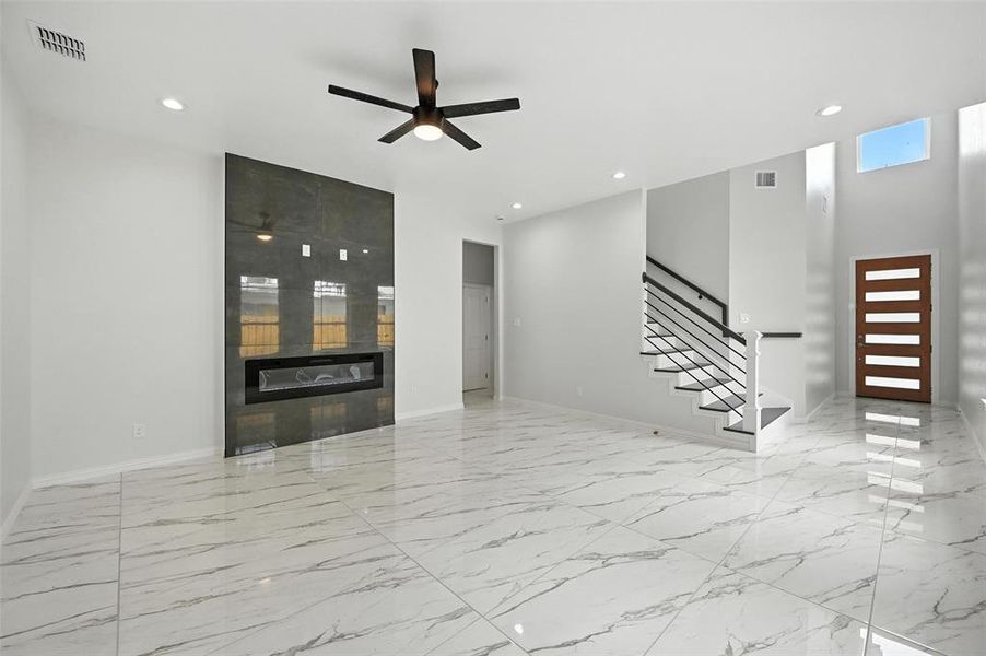 Unfurnished living room featuring light marble finish flooring, stairway, recessed lighting, ceiling fan, and a fireplace