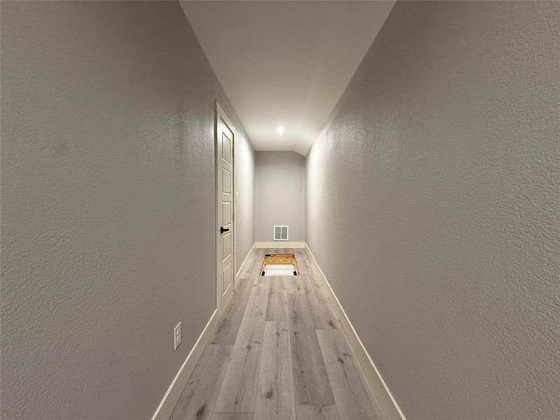 Corridor featuring a textured wall and light wood-style flooring